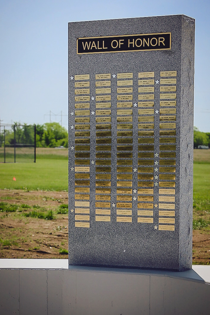 Close-up of the granite "Wall of Honor" monument showing rows of gold name plaques with service branches.